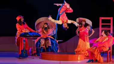 Miembros actuando de "Alboroto", de la compañía sevillana Truca Circus. predominan los tonos rojizos.