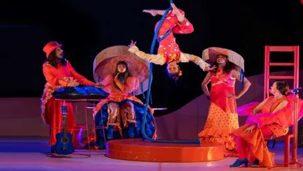 Miembros actuando de "Alboroto", de la compañía sevillana Truca Circus. predominan los tonos rojizos.