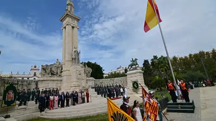 Bandera de España izada ante el Monumento a la Constitución de 1812, en la plaza de España de Cádiz, con autoridades y miembros de la Guardia Civil situados frente al monumento durante el acto inaugural de la Semana de la Guardia Civil.