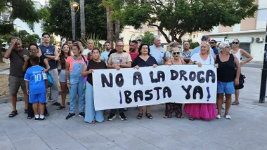 Grupo de vecinos y vecinas del Cerro del Moro concentrados en una plaza del barrio. En primera fila, varias personas sostienen una gran pancarta blanca en la que puede leerse: “No a la droga. ¡Basta ya!”.