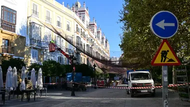 Plaza de España de Cádiz durante los trabajos de retirada de instalaciones, con una grúa, un vehículo de trabajo, vallas y señalización junto a los edificios de la plaza.