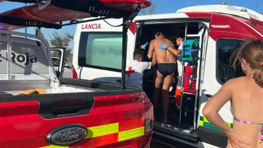 Un bañista, vestido con un bañador negro, entra asistido por personal de Cruz Roja en un vehículo de emergencias tras su rescate en Sancti Petri. En primer plano se observa otro vehículo de Cruz Roja utilizado en el operativo.