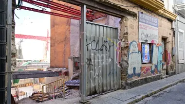 Vista de los trabajos en el inmueble del barrio del Mentidero, donde todavía permanece el antiguo cartel de la promoción inmobiliaria que quedó paralizada hace 14 años.