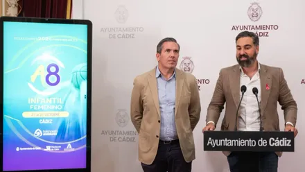 Dos representantes institucionales presentan el Campeonato de Andalucía de Baloncesto Infantil Femenino en el Ayuntamiento de Cádiz. A la izquierda aparece el cartel del torneo, con las fechas del 23 al 25 de octubre.