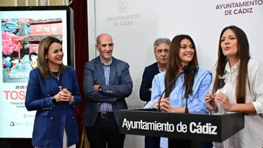 Míriam Ballesteros habla ante los micrófonos junto a Brenda García durante la presentación de los Tosantos 2026 en el Ayuntamiento de Cádiz, acompañadas por representantes municipales y de las entidades colaboradoras.