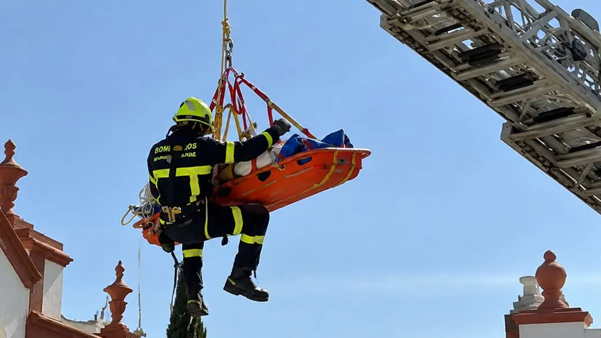 Un bombero rescata a un trabajador, en una camilla naranja, de una azotea en San Fernando.