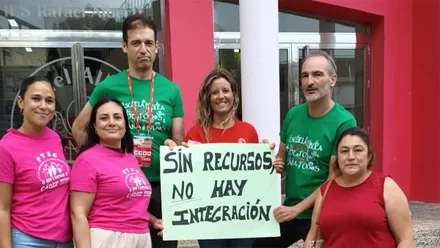 Varias personas posan ante la entrada del IES Rafael Alberti de Cádiz durante una protesta, sosteniendo un cartel en el que se lee “Sin recursos no hay integración”.