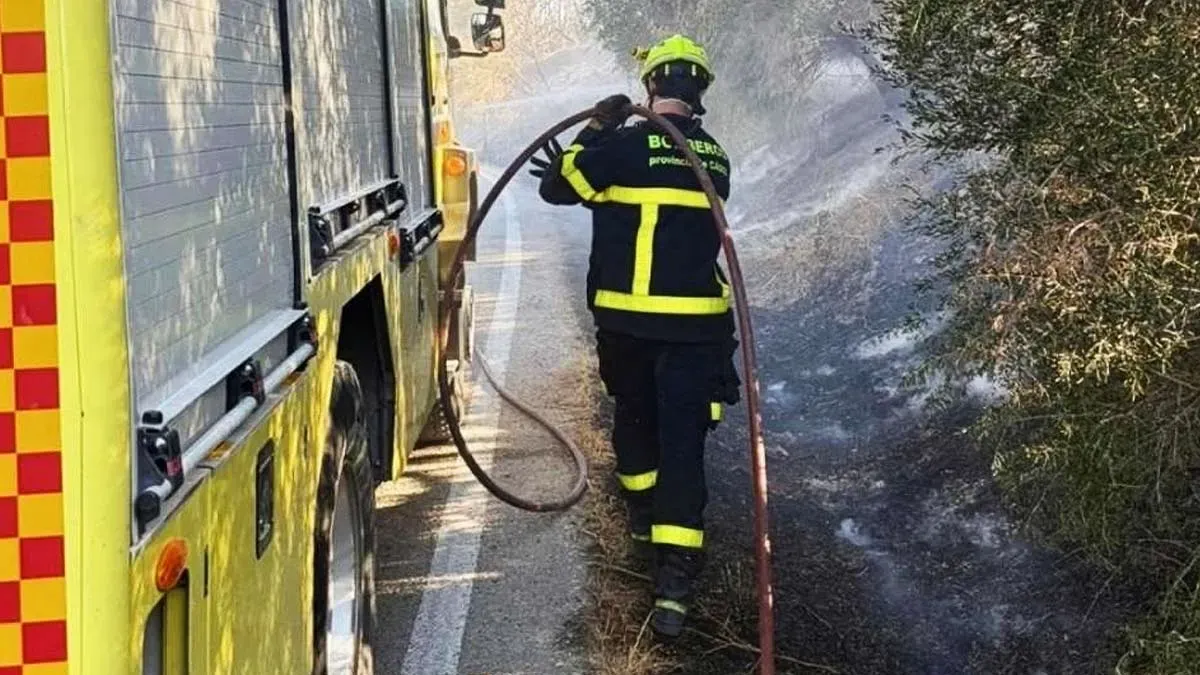 Bombero junto a un camión con una manguera de agua para sofocar el incendio.