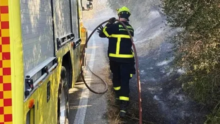Bombero junto a un camión con una manguera de agua para sofocar el incendio.