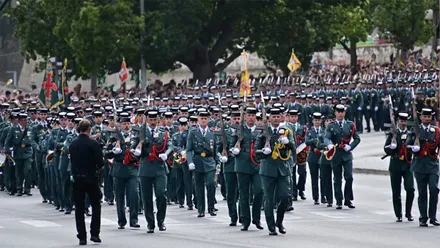 Amplia formación de guardias civiles bajando por la Cuesta de las Calesas hacia la plaza de Sevilla y la Avenida del Puerto de Cádiz, con mandos y enseñas al frente y numeroso público al fondo.