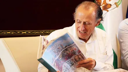 Cara de sorpresa del alcalde de Chiclana, José María Román, con el álbum de Holy Cards.