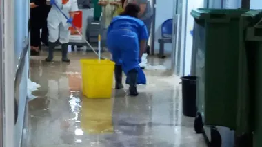 Pasillo arriado de agua y limpiadora recogiendo agua.