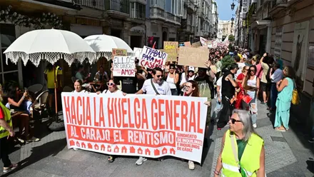 Cabecera de la manifestación por la vivienda recorriendo la calle Ancha de Cádiz con una pancarta en la que se lee "Hacia la huelga general".