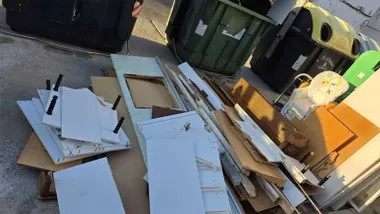 Muchos tableros y enseres de madera de muebles tirados en El Puerto junto a contenedores.