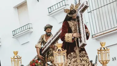 Jesús Nazareno de Arcos de la Frontera porta la cruz acompañado por el Cirineo durante una salida procesional por las calles de la localidad.