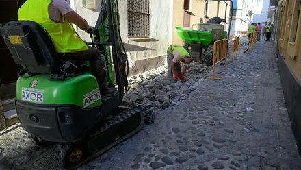 Dos operarios trabajan con maquinaria en la retirada del pavimento de cantos rodados de la calle Mirador de Cádiz, en el barrio de Santa María, durante las obras de reurbanización.