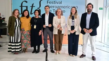 Siete personas, cinco mujeres y dos hombres, entre representantes institucionales y de la organización del FIT de Cádiz, posan de pie ante un panel con el logotipo del festival durante su presentación oficial.