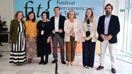 Siete personas, cinco mujeres y dos hombres, entre representantes institucionales y de la organización del FIT de Cádiz, posan de pie ante un panel con el logotipo del festival durante su presentación oficial.