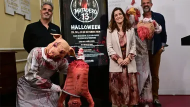 La concejala Gloria Bazán posa junto a dos representantes de la organización y dos actores disfrazados de animales terroríficos, con el cartel de "Matadero 13" al fondo, durante la presentación de Halloween 2026 en Cádiz.