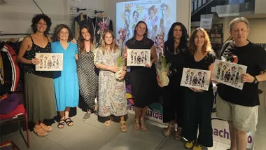 Grupo de participantes en la presentación del calendario coeducativo de 2027 en Cádiz, varias de ellas sosteniendo ejemplares de la publicación, con una proyección sobre mujeres en la educación al fondo.