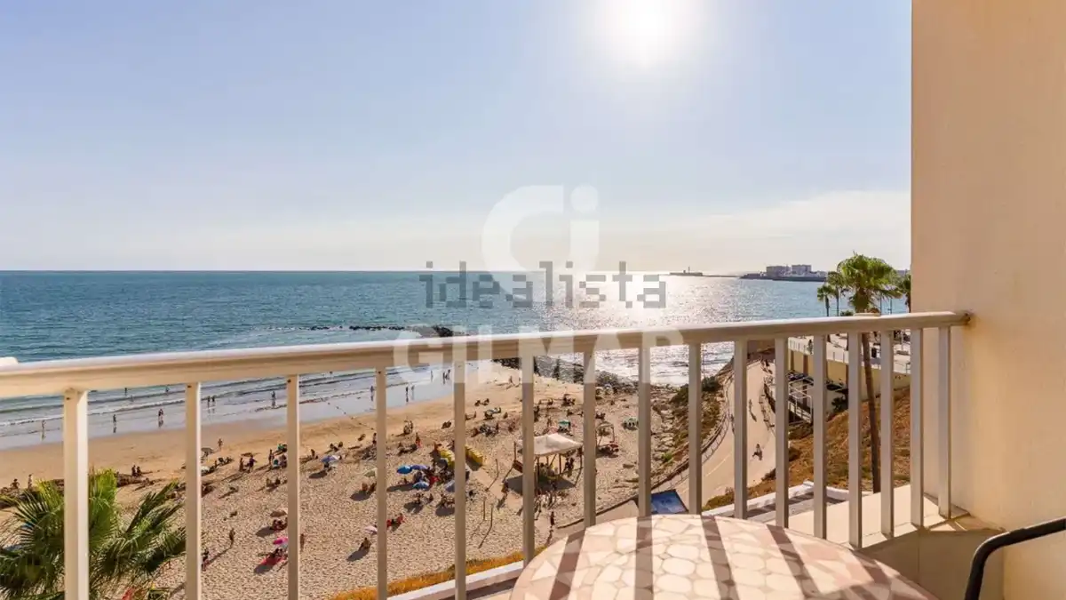 Balcón de la vivienda con una mesa y varias sillas frente a la playa de Santa María del Mar, con el océano Atlántico al fondo.