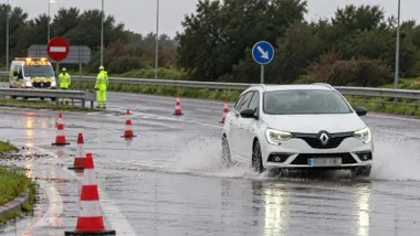 Vehículo blanco por una carretera inundada.