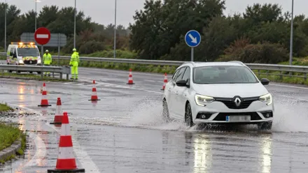 Vehículo blanco por una carretera inundada.