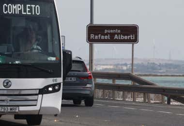 Rótulo con el nuevo nombre Puente Rafael Alberti y dos vehículos circulando por él.